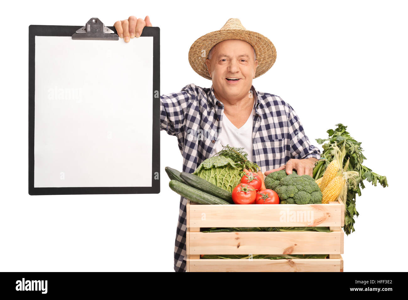 Cheerful elderly farmer behind a crate full of vegetables holding a ...