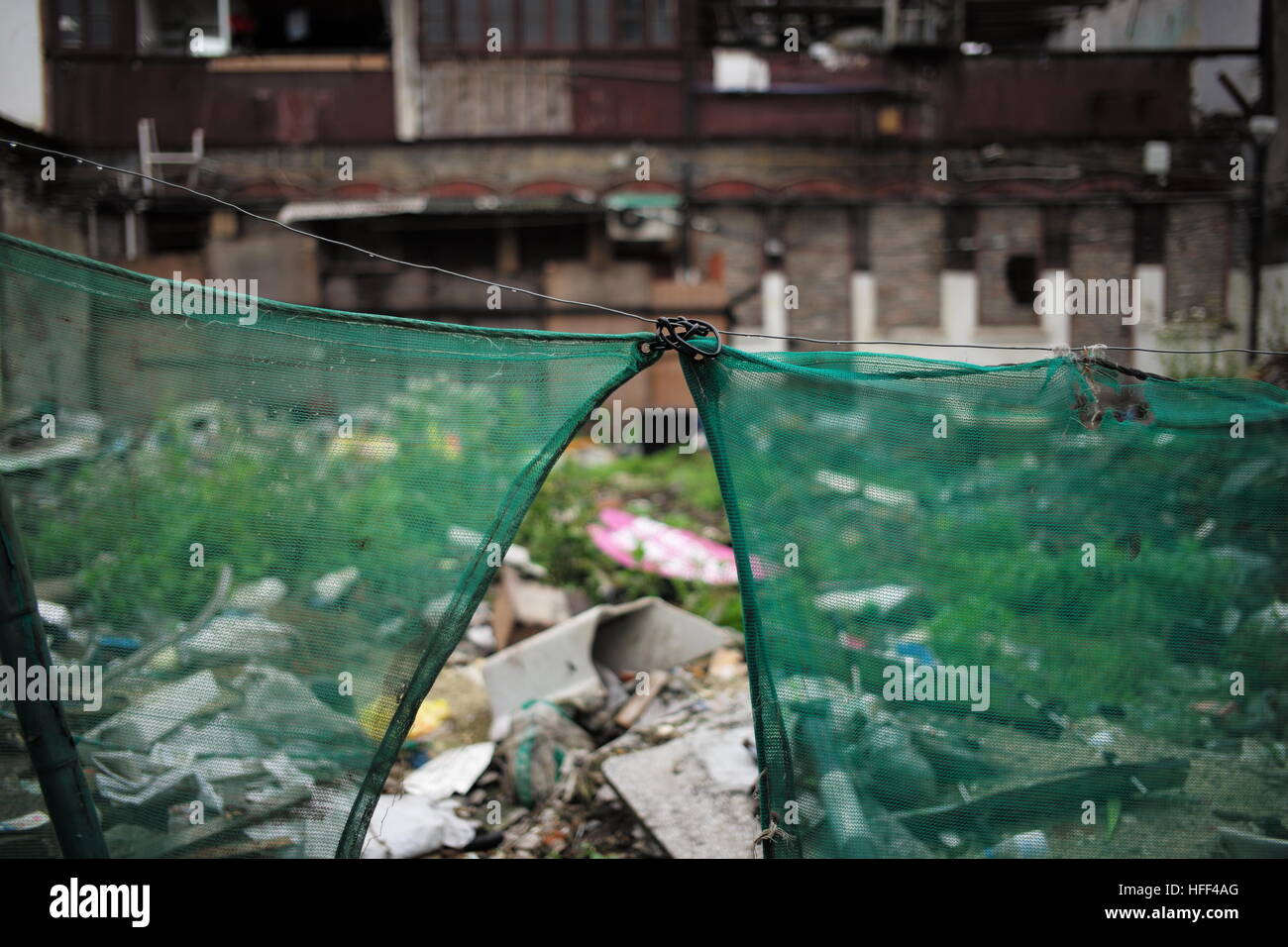 Destruction of Shanghai Longtangs. -  26/04/2016  -  China / Shanghai  -  The work have to be covered to avoid pollution. Destruction of Shanghai Longtangs. At the beginning of the '80s, the majority of the population was living in Longtangs, that it to say small villages into cities. Ther destruction follows the growth curve, thus hectares of land await the promoter who will decide to build a Mall or a bar of buildings. Some owners are resisting and keep living in their home. Water and electricity are then cut off. The othr receive a compensation and are sent to the suburbs. Everything is rec Stock Photo