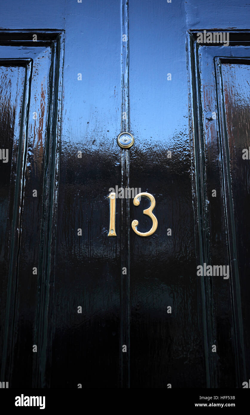Black painted front door with number thirteen. Stock Photo