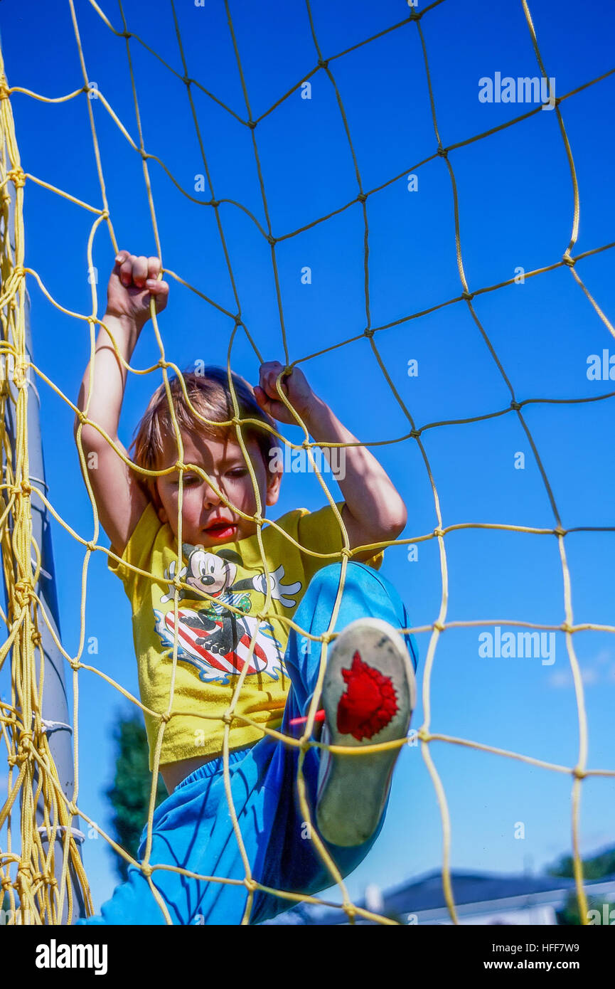 Young boy plays on schoolyard recreational equipment. Stock Photo