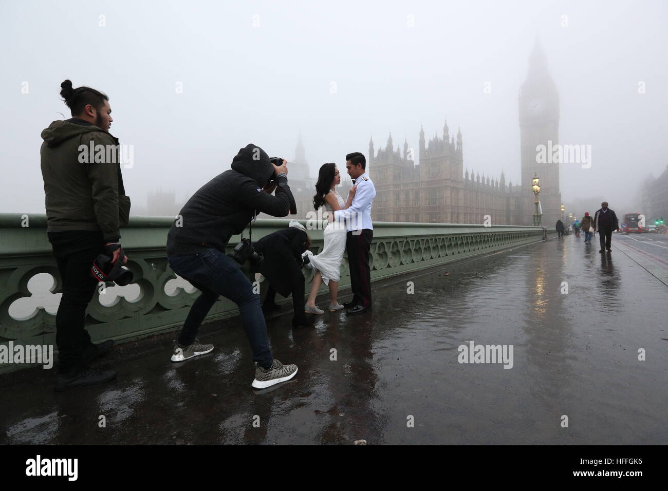 A Thai couple pose for their pre-wedding photographs, ahead of their marriage in July, as fog shrouds the Houses of Parliament in central London after forecasters warned of visibility as low as 100 metres with fog and sub-zero temperatures across swathes of England. Stock Photo