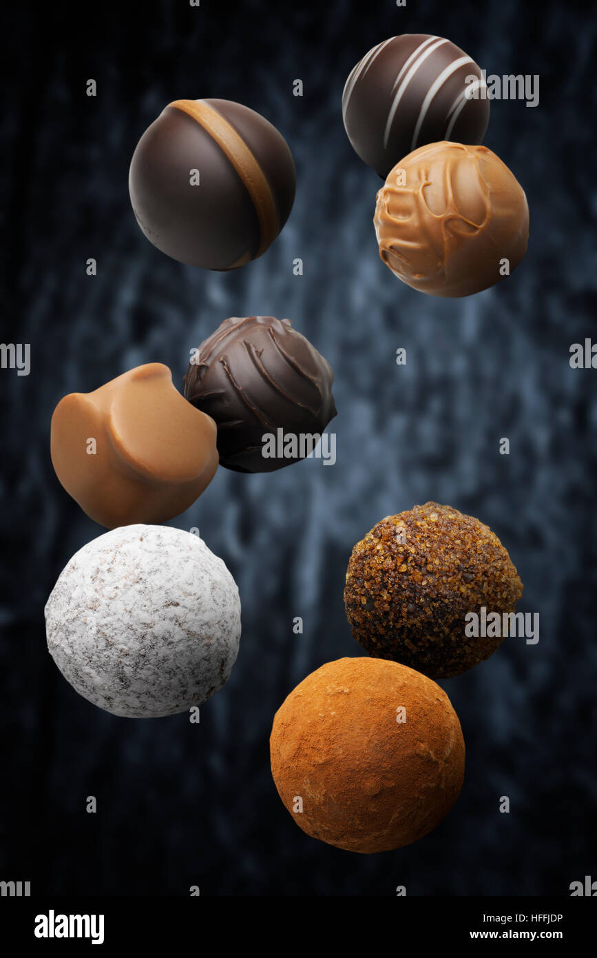 Assorted multi flavoured pralines floating against dark background Stock Photo