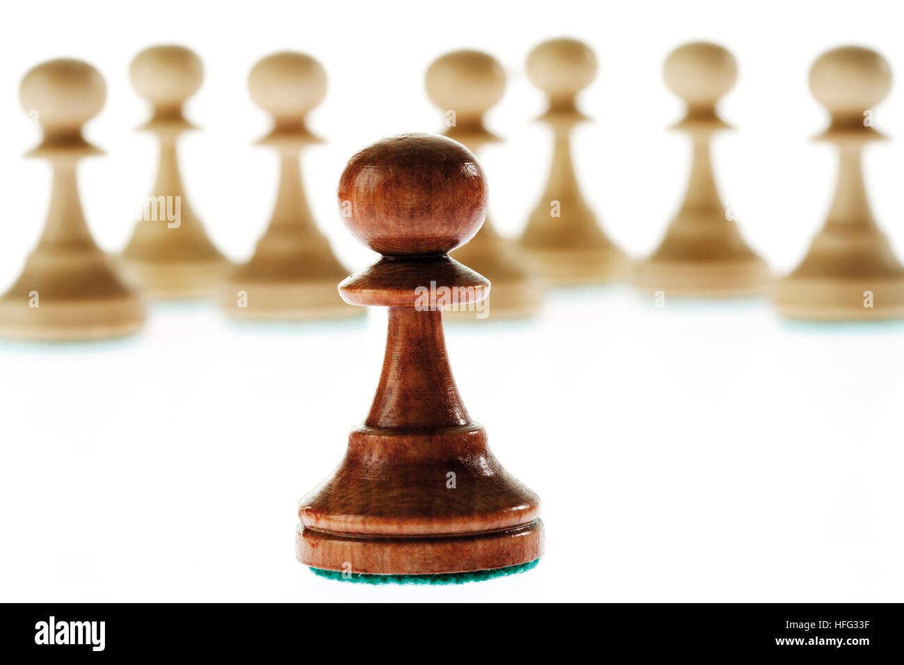 Chess pieces: single brown pawn standing apart from many white pawns Stock Photo