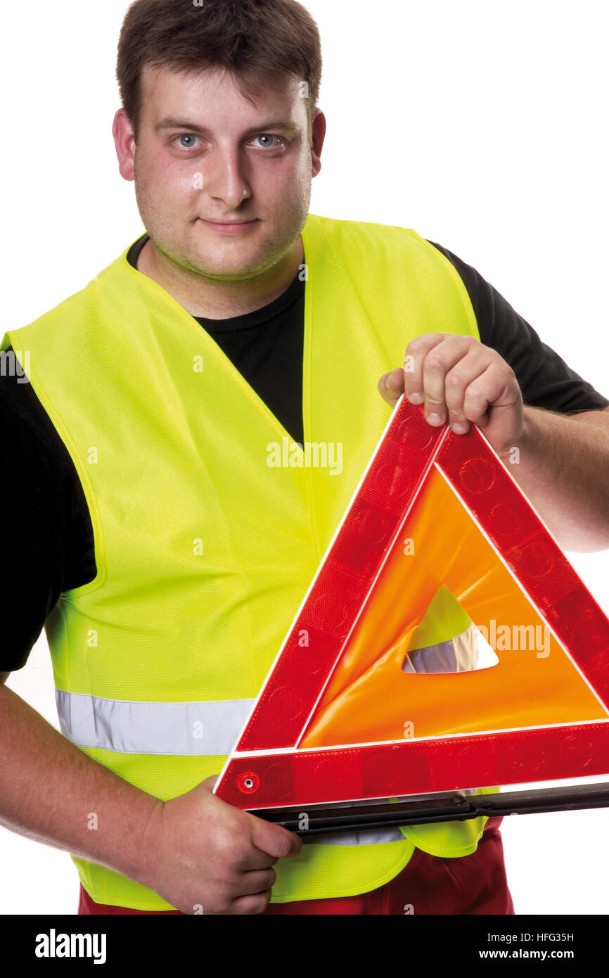 Construction worker wearing a yellow high-visibility vest holding a caution triangle Stock Photo
