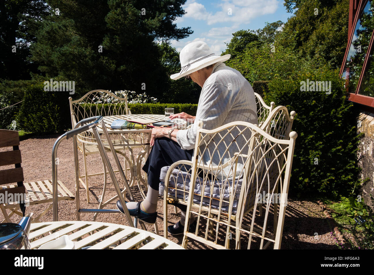 Elderly lady enjoying tea in the afternoon sun at a country estate. Stock Photo