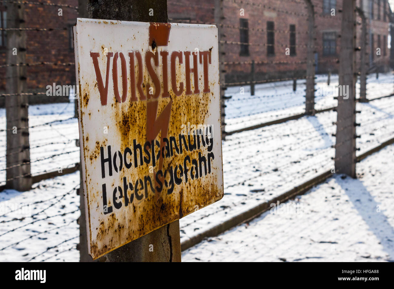 Sign 'vorsicht hochspannung lebensgefahr' was seen in front of some of the perimeter fences which were electrified at Auschwitz. Stock Photo