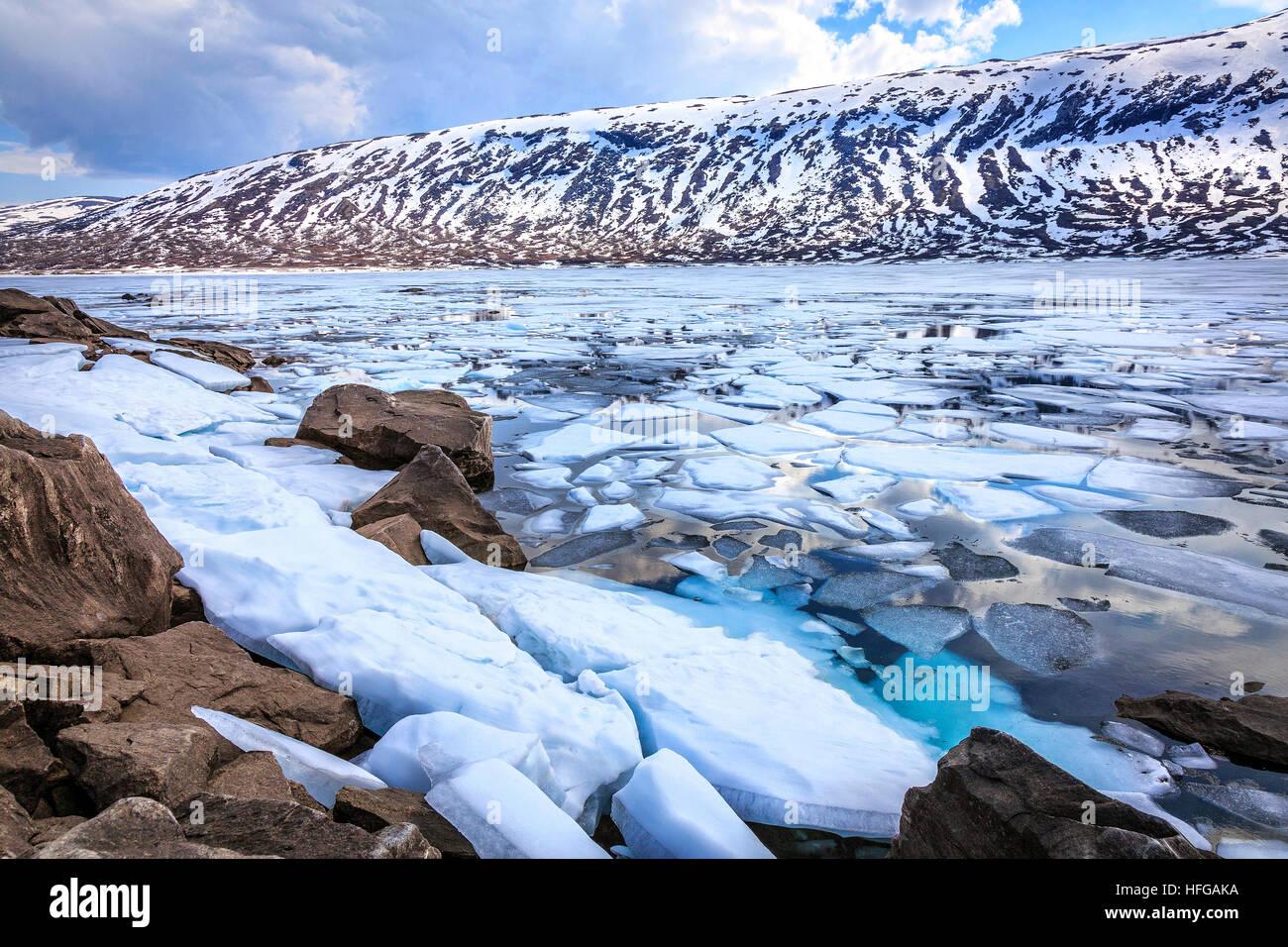 The ice breaking up on the lake in Fjordane, Norway in Spring. Isolated pockets of ice remain on the land. Stock Photo