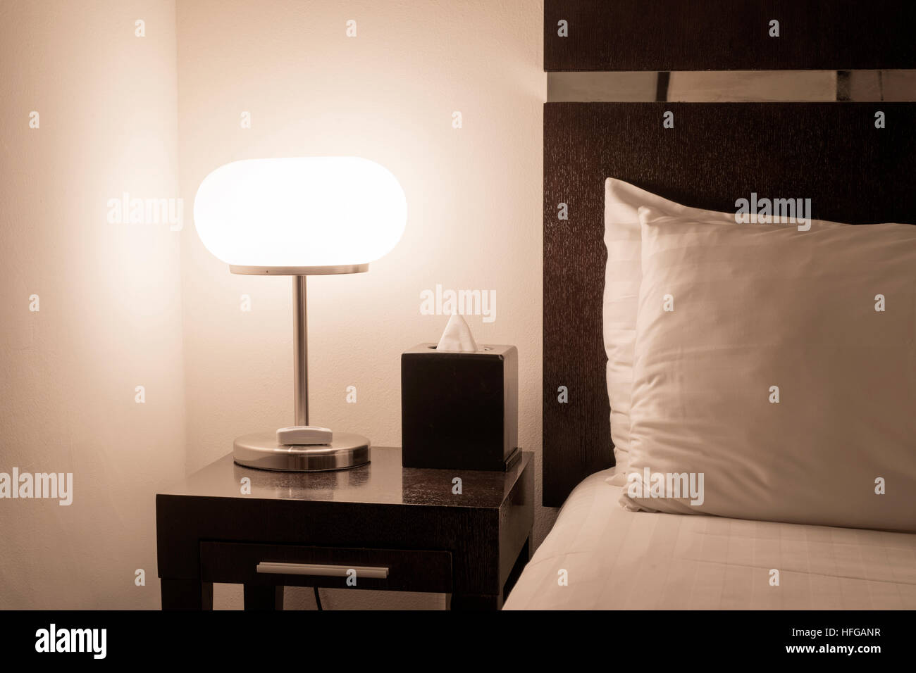 hotel room interior with illuminated bed light on wooden table Stock Photo