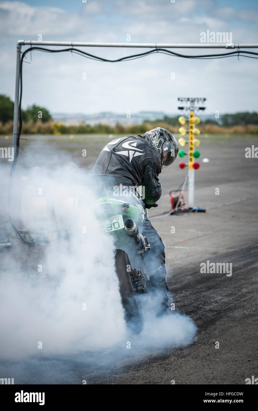 A motorcycle rider performs a burnout, to warm up the tire, before a drag racing event. Stock Photo