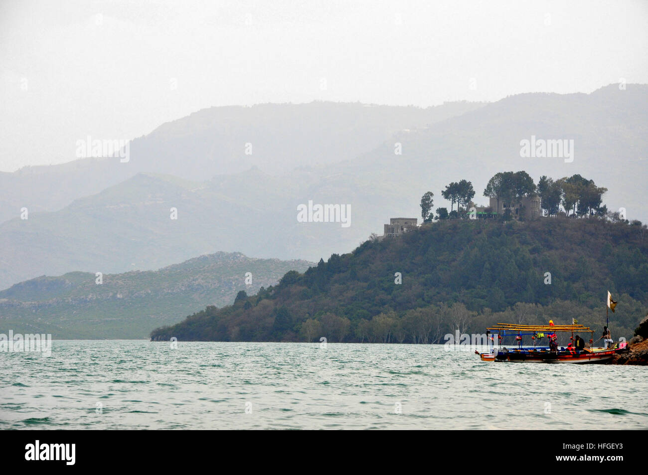 Boat on dock at Khanpur dam, Pakistan with clouds green mountain range in the background. Stock Photo