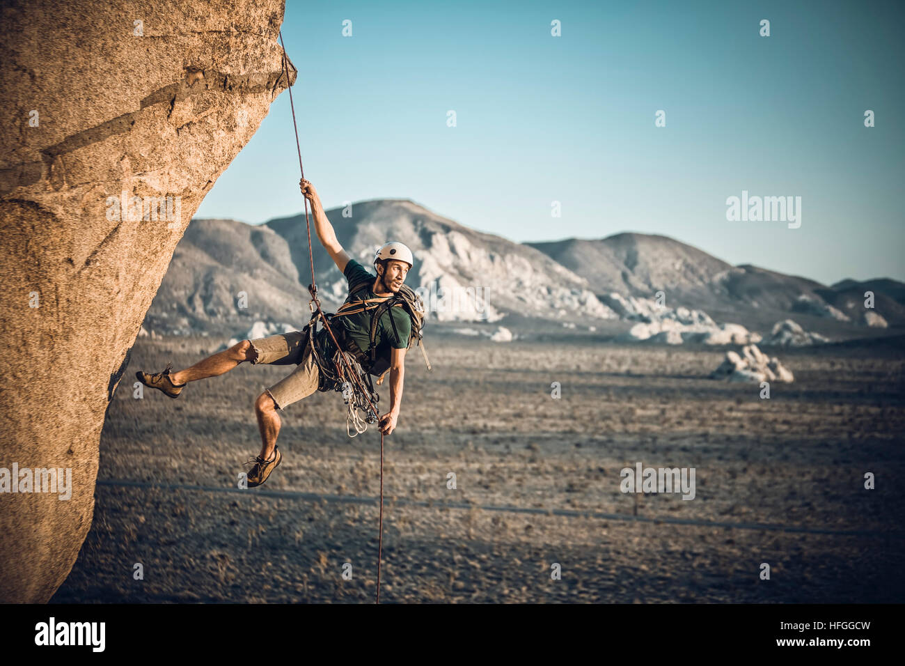 A rock climber rappelling past an overhang in Joshua Tree National Park