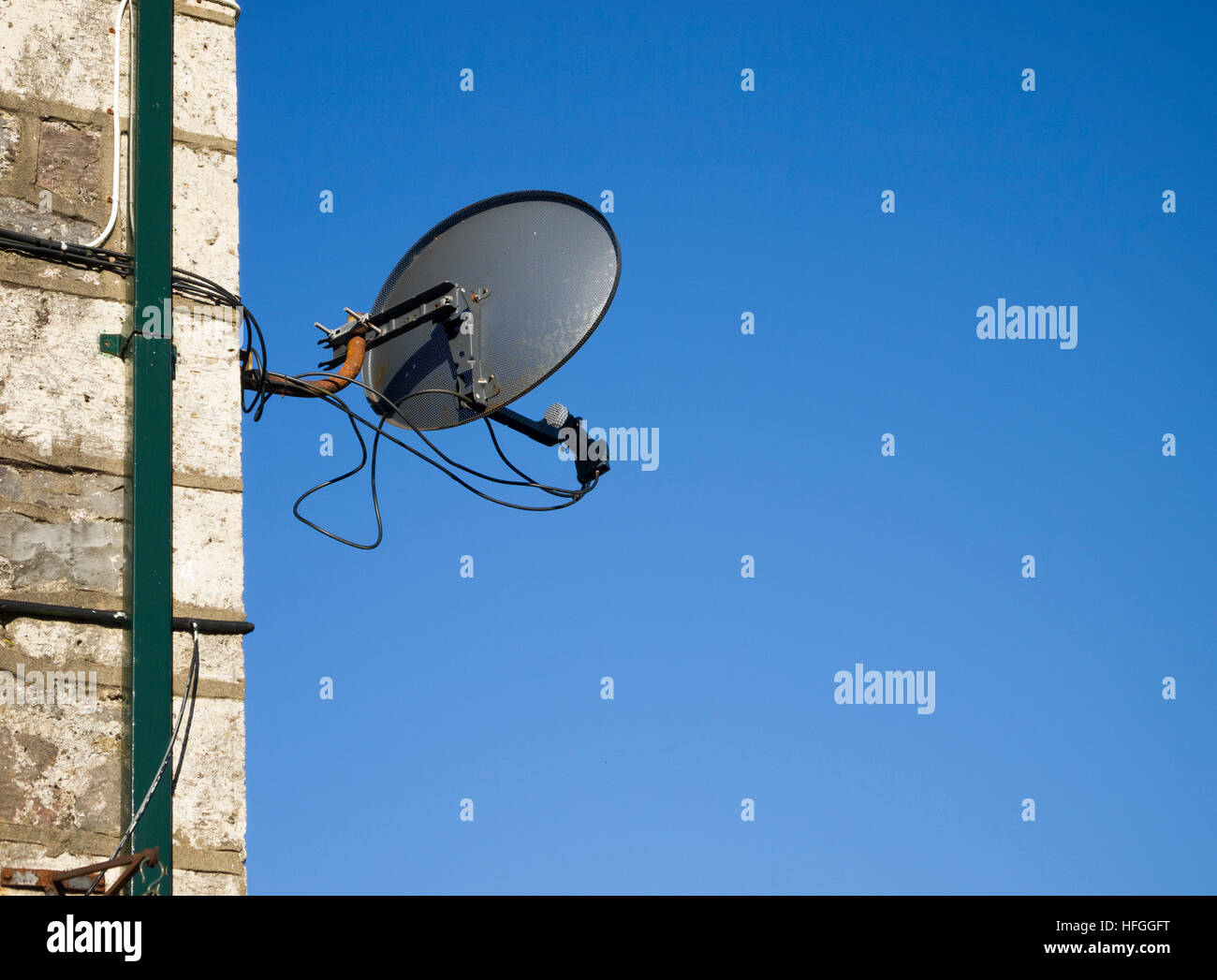 satellite dish mounted on wall with blue sky Stock Photo