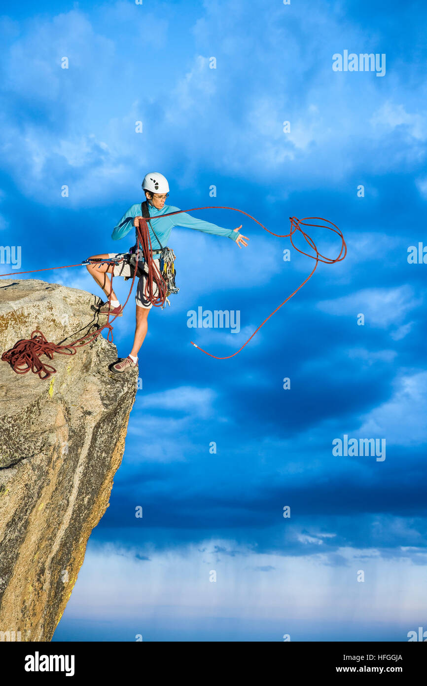 Female climber dangeling from the edge of a sheer rock mountain Stock