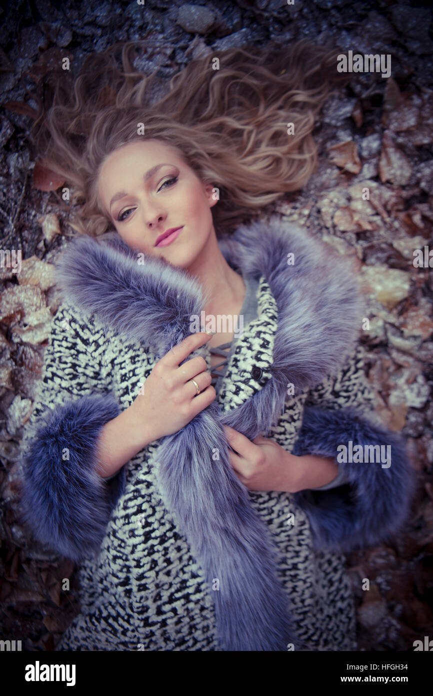 Photographic modeling as a career in the UK: A young slim attractive 20 year old caucasian woman girl with long blonde hair  lying on her back on the ground on a cold  frosty day looking like an Ice Queen Stock Photo