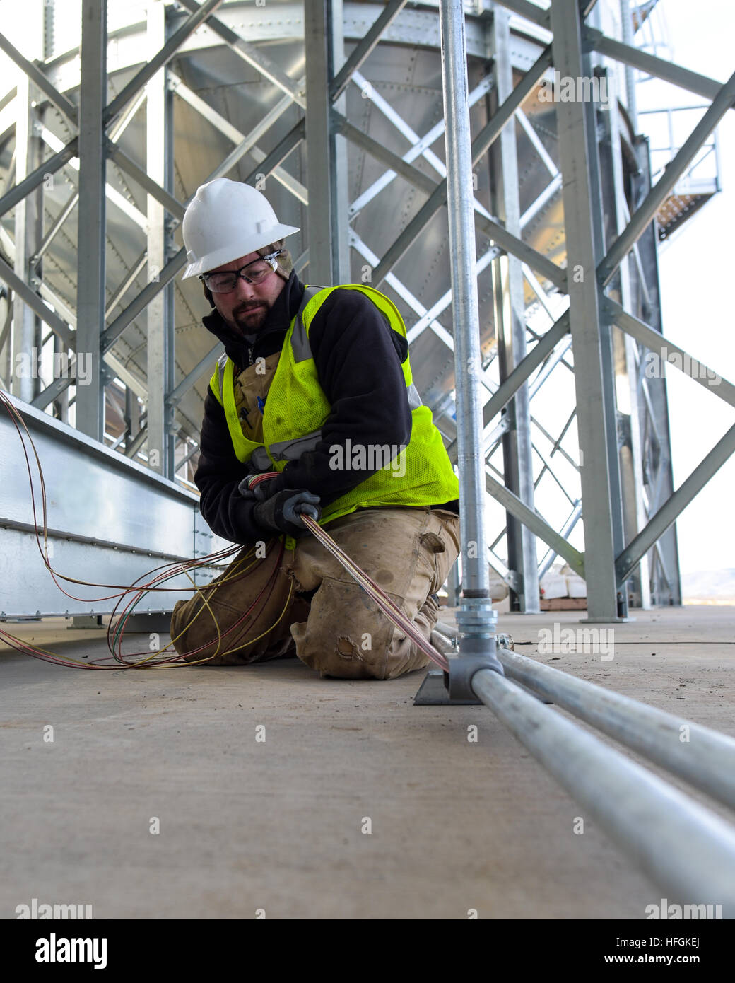 Real Electrician Pulling Wires Through Conduit at an Industrial Site Stock Photo