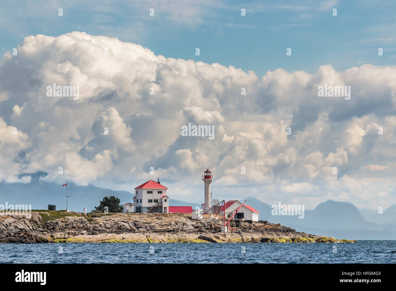 A close, water level view of Entrance Island Lighthouse off Gabriola Island, with blue sky and cumulus clouds towering over Howe Sound in the distance Stock Photo