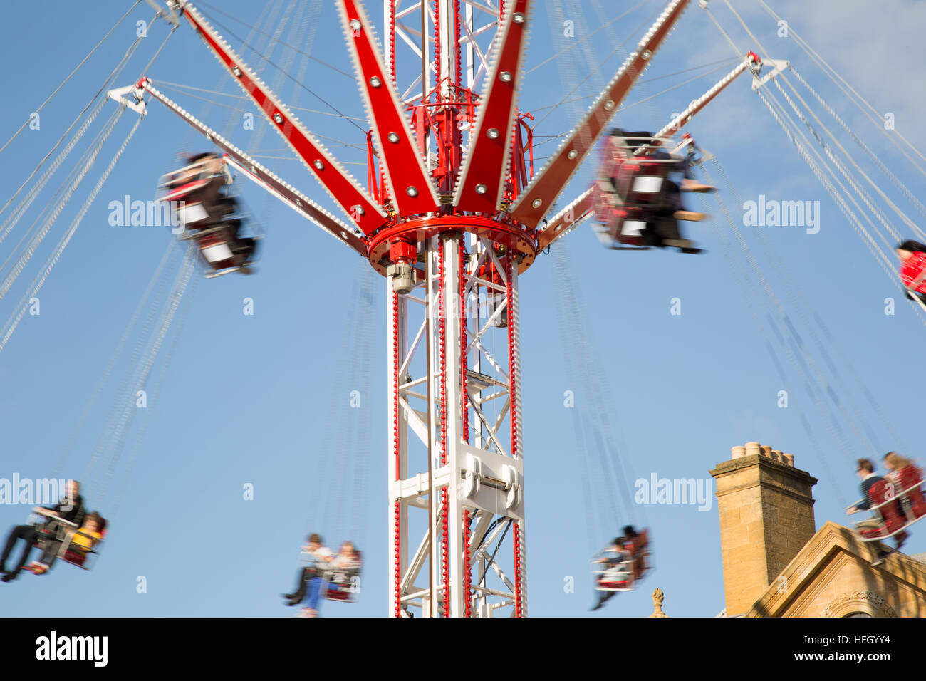 People enjoying the Skyrider at St Giles Fair Oxford as they swing round the central column against a blue sky background. Stock Photo