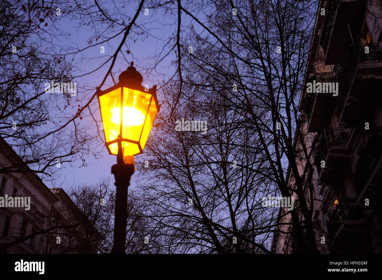 Berlin, Germany. 30th Dec, 2016. A lamp is lit with yellow light on Husemann-Strasse at twighlight in the neighborhood of Prenzlauer Berg in Berlin, Germany, 30 December 2016. Photo: Jens Kalaene/dpa-Zentralbild/ZB/dpa/Alamy Live News Stock Photo