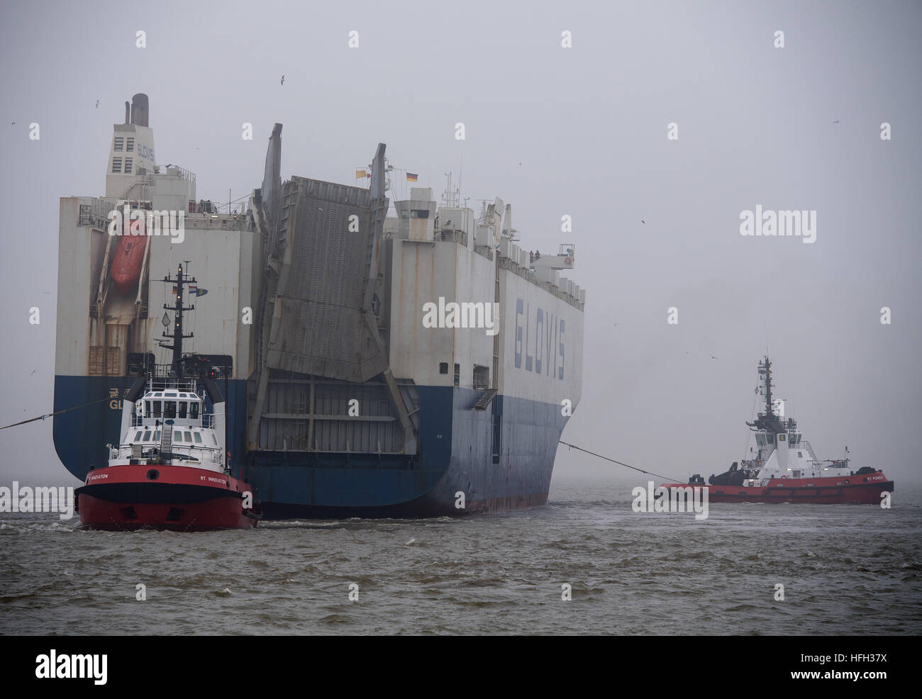 Bremerhaven, Germany. 31st Dec, 2016. The car transport ship 'Glovis Coron, ' wrecked in the storm 'Barbara, ' arrives in thick fog to the Kaiserschleuse lock in Bremerhaven, Germany, 31 December 2016. The Korean freighter, loaded with tanks, among other things, listed after the load shifted and became distressed at sea off the East Frisian island of Wangerooge. By adjusting the ballast water tank, the list could be reduced from 15 to 5 degrees. Experts will secure and re-lash the load in Bremerhaven. Photo: Ingo Wagner/dpa/Alamy Live News Stock Photo