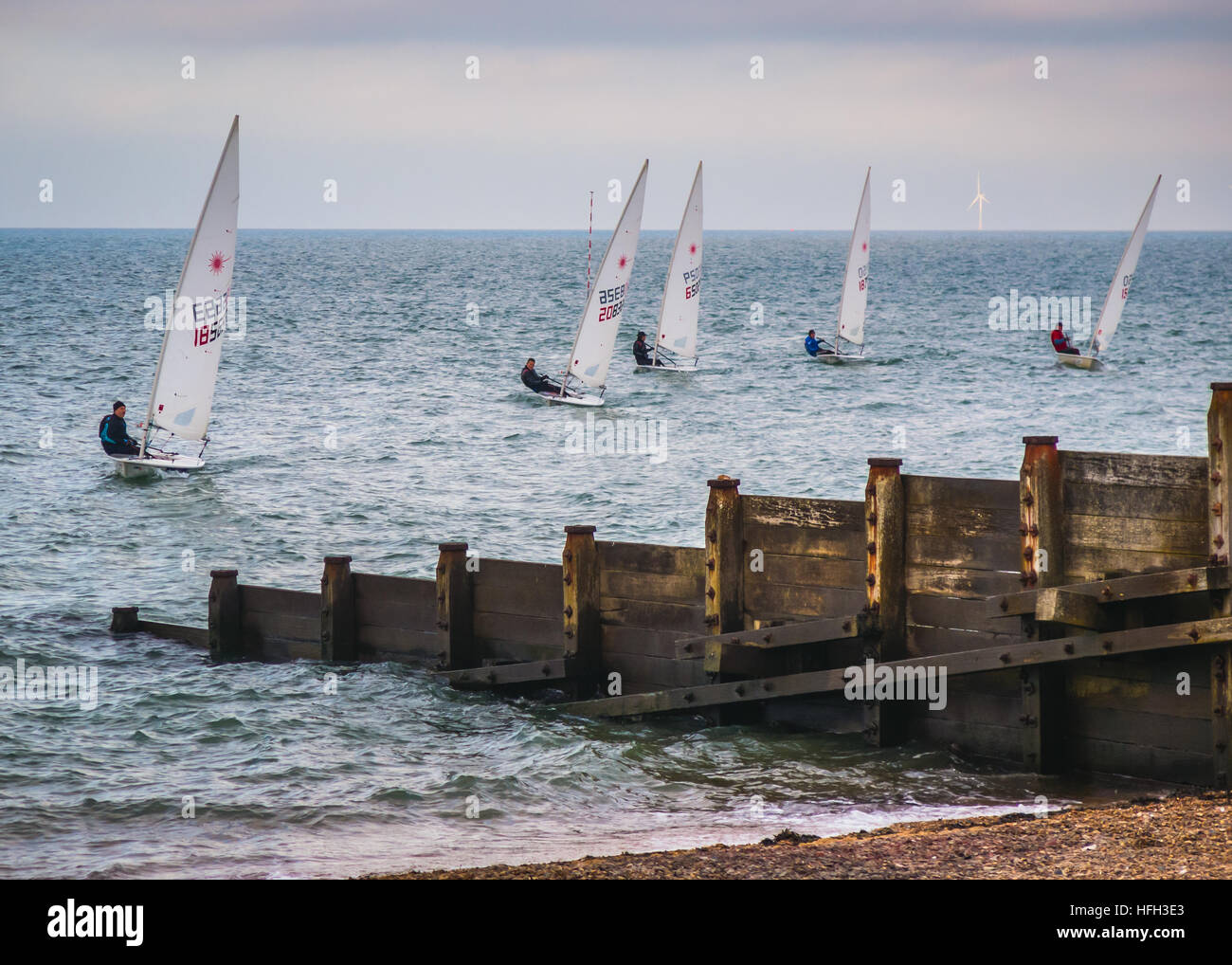 Whitstable, UK. 31st Dec, 2016. Whitstable, UK - Dec 31 2016  Members of Whitstable yacht club sailing in dinghy laser boats in front of the distinctive wooden groynes on Whitstable beach on New Years Eve 2016. © CBCK-Christine/Alamy Live News Stock Photo