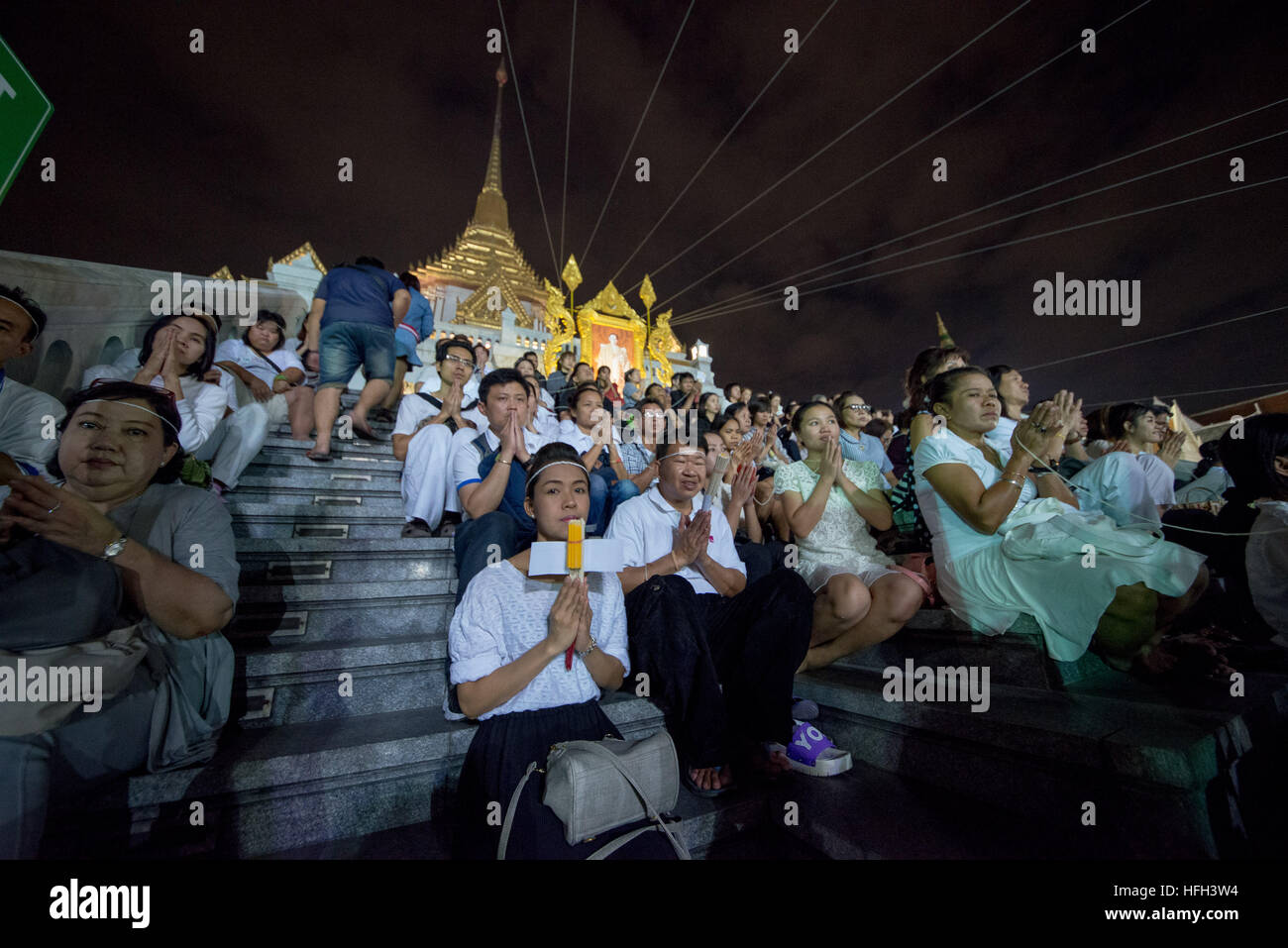 Bangkok, Thailand. 31st Dec, 2016. The New Year 2017 celebrations started in Bangkok in line with the mourning period of the late King Bhumibol Adulyadej. At Wat Traimit Temple thousands of people observe 89 seconds of silence, signifying the age of the late King. The sacred white thread ''˜Sai-sin' was in use at a temple ceremony. © Velar Grant/ZUMA Wire/Alamy Live News Stock Photo
