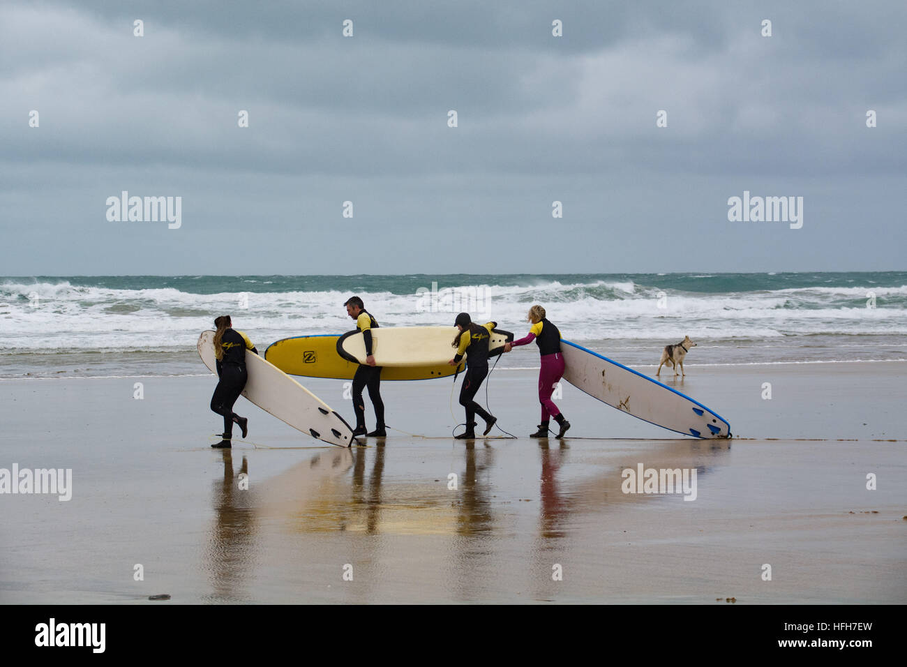 Newquay, Cornwall, UK. 1st January 2017. UK Weather. Surfers and walkers braving strong, cold, north easterly winds taking to the sea for the traditional new years day outing to the beach. Credit: cwallpix/Alamy Live News Stock Photo