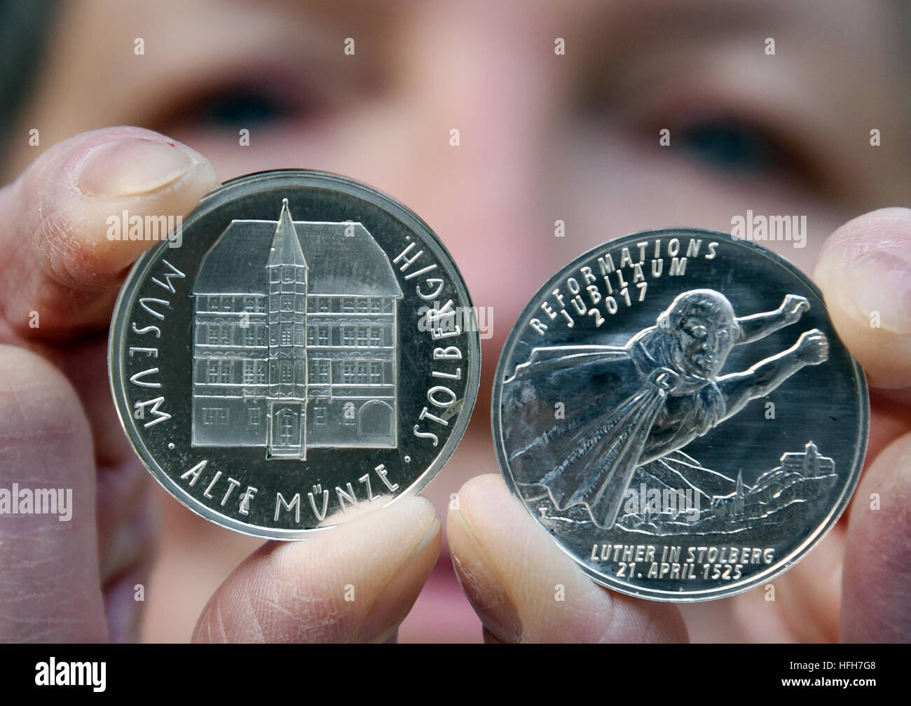 Monika Frischke holds up the new 2017 medal that shoes the reformer Martin Luther as superman in the Coin Museum in Stolberg/Suedharz, Germany, 01 January 2017. The silver coin recalls the reformer's stay in Stolberg on 21 April 1525 on the occasion of the anniversary of the Reformation this year. On the medal Luther is flying with balled fists and a flapping cape over the city. It should be symbolically and comically expressed that Luther's thoughts transcended the boundaries of his time. Photo: Waltraud Grubitzsch/dpa-Zentralbild/dpa Stock Photo