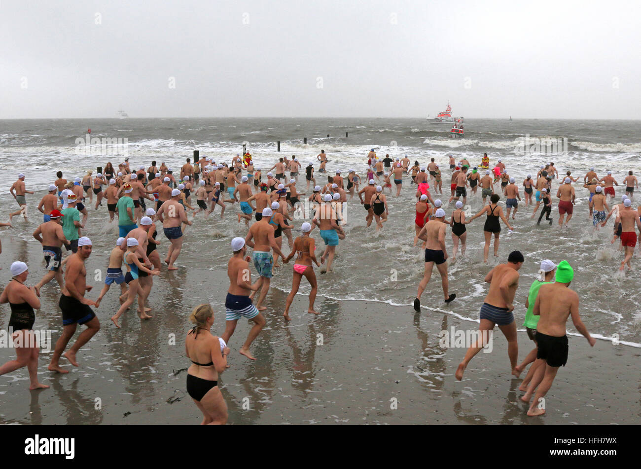 Norderney, Germany. 01st Jan, 2017. Courageous participants run into the cold 4-degree North Sea during a New Year's swim on Norderney, Germany, 01 January 2017. The air was not much warmer and there was also a brisk wind. Thousands of spectators watched the spectacle. Photo: Sabine Sykora/dpa/Alamy Live News Stock Photo