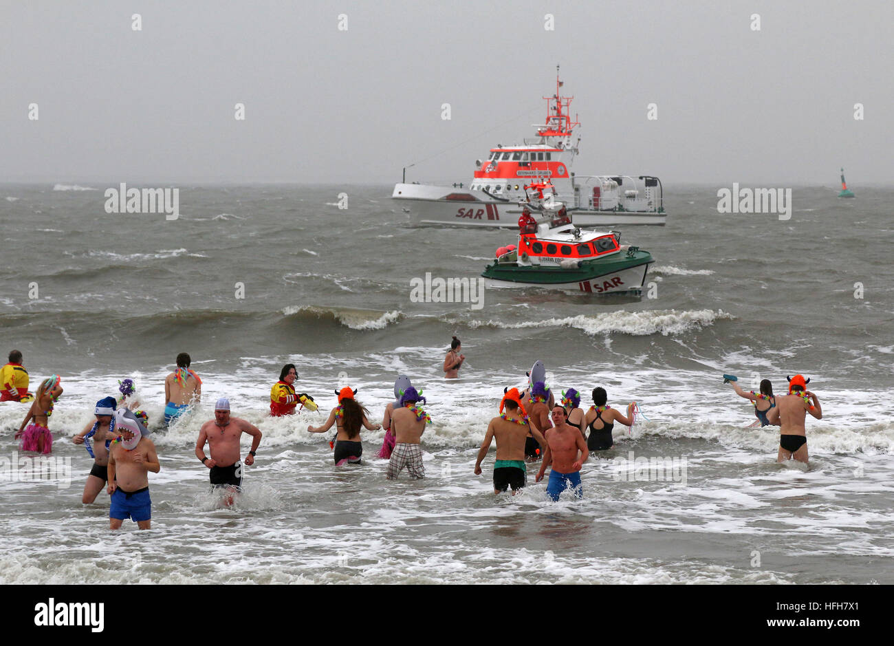 Norderney, Germany. 01st Jan, 2017. Courageous participants run into the cold 4-degree North Sea during a New Year's swim on Norderney, Germany, 01 January 2017. The air was not much warmer and there was also a brisk wind. Thousands of spectators watched the spectacle. Photo: Sabine Sykora/dpa/Alamy Live News Stock Photo