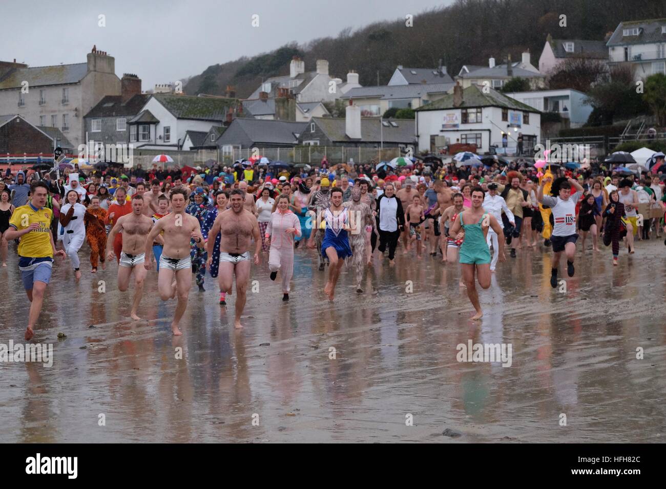 Lyme Regis, Dorset, UK. 1st Jan, 2017. Hundreds of New Year revellers take to the sea in the “Lyme Lunge” to raise funds for Macmillan Cancer Support. The annual event was watched by over a thousand spectators who gathered on Lyme Regis Cobb Beach to support the event. © Tom Corban/Alamy Live News Stock Photo