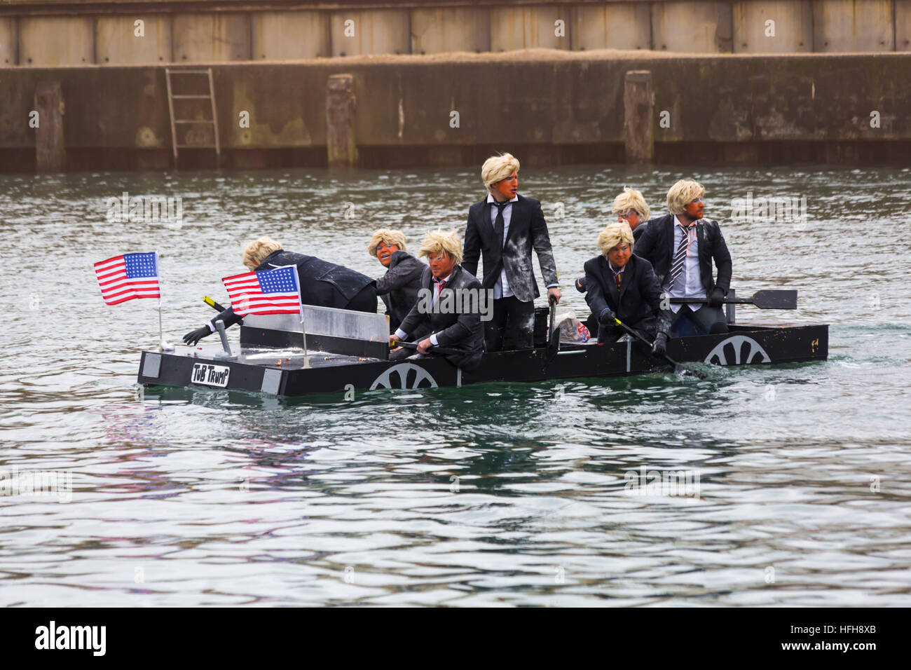 Poole, Dorset, UK. 1st January, 2017. Hundreds turn out to watch the New Years Day Bath Tub Race. A variety of unusual craft take to the water to race, having fun throwing eggs and flour, firing water cannons and capsizing competing craft. Trumps with wigs hair and make up in Tub Trump Stock Photo