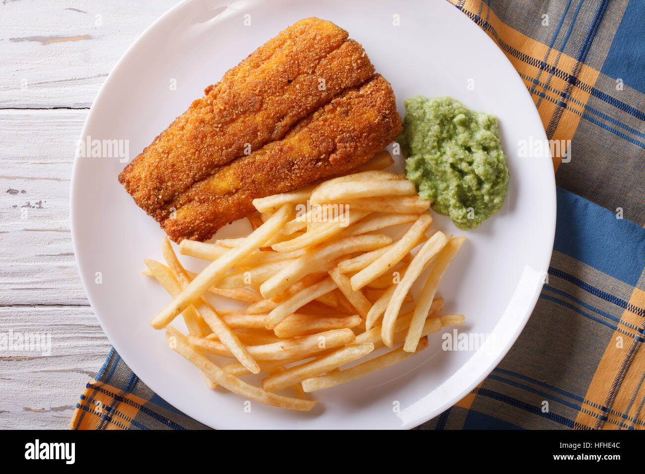 English food: fried fish in batter with chips and pea puree close-up on a plate. horizontal view from above Stock Photo