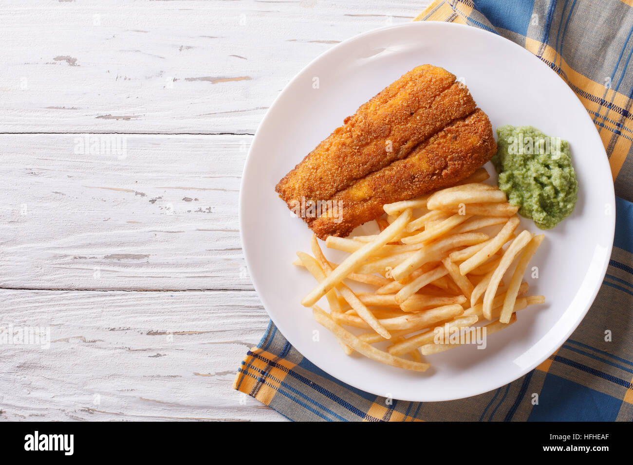 English food: fried fish in batter with chips and pea puree on a plate. horizontal view from above Stock Photo