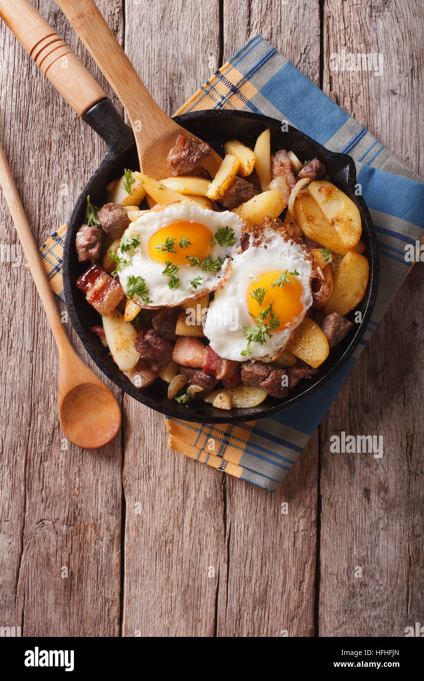 Tyrolean fried potatoes with meat, bacon and eggs in a pan. vertical