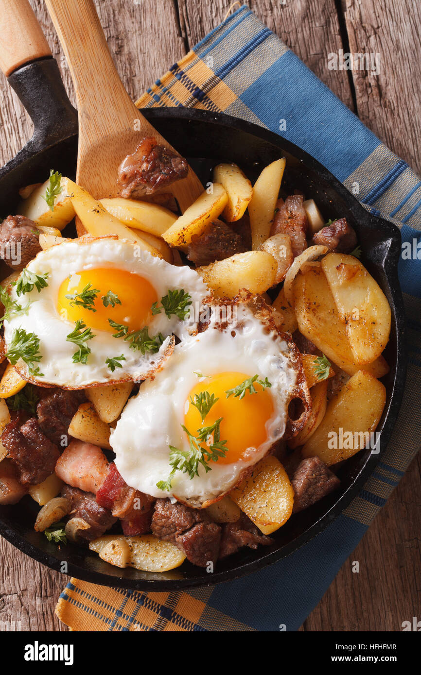 Tyrolean fried potatoes with meat and eggs in a pan closeup. vertical