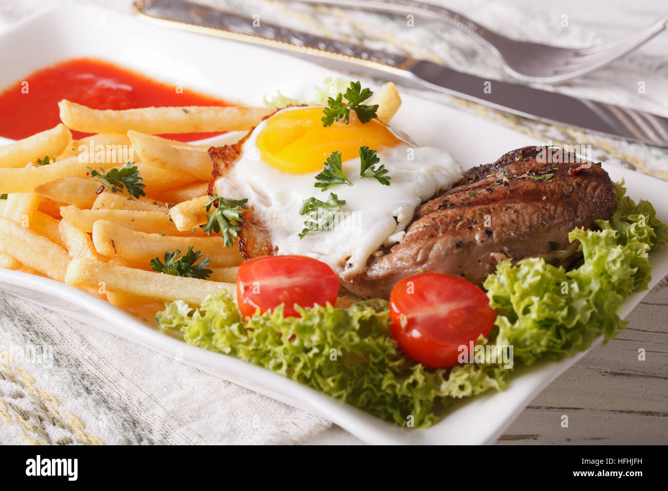 Fried potatoes, egg, grilled beefsteak with ketchup on a plate