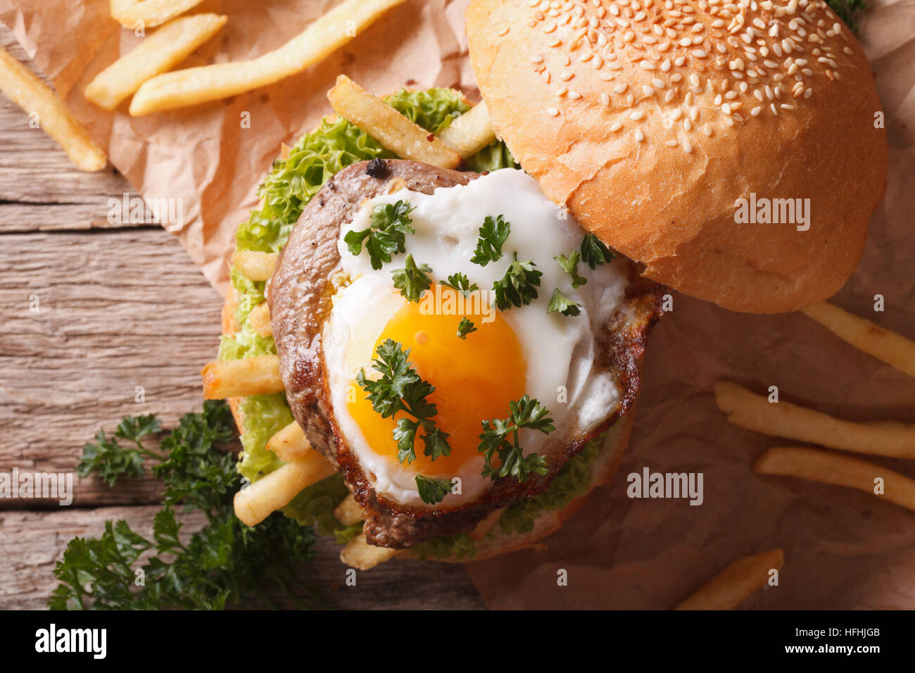sandwich with grilled meat, a fried egg and French fries close-up. horizontal view from above Stock Photo