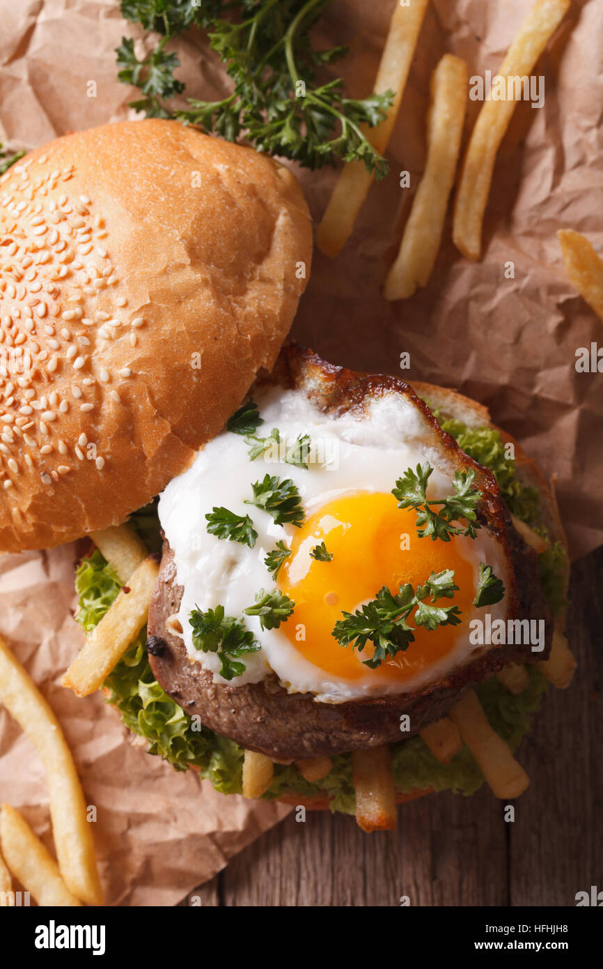 sandwich with grilled meat, a fried egg and French fries close-up. vertical top view Stock Photo