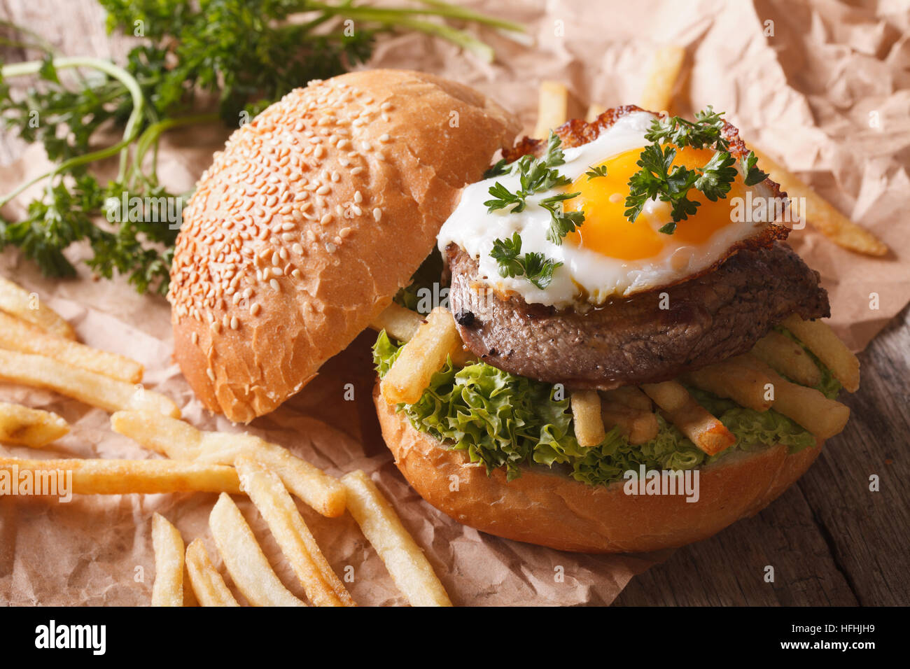 Rustic sandwich with beefsteak, fried egg and French fries. Horizontal Stock Photo