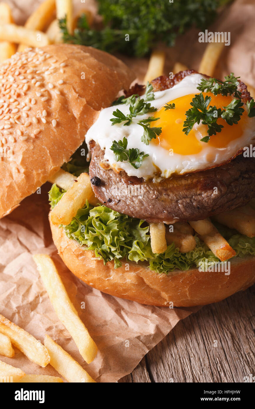 Rustic sandwich with beefsteak, fried egg and French fries close-up. vertical Stock Photo