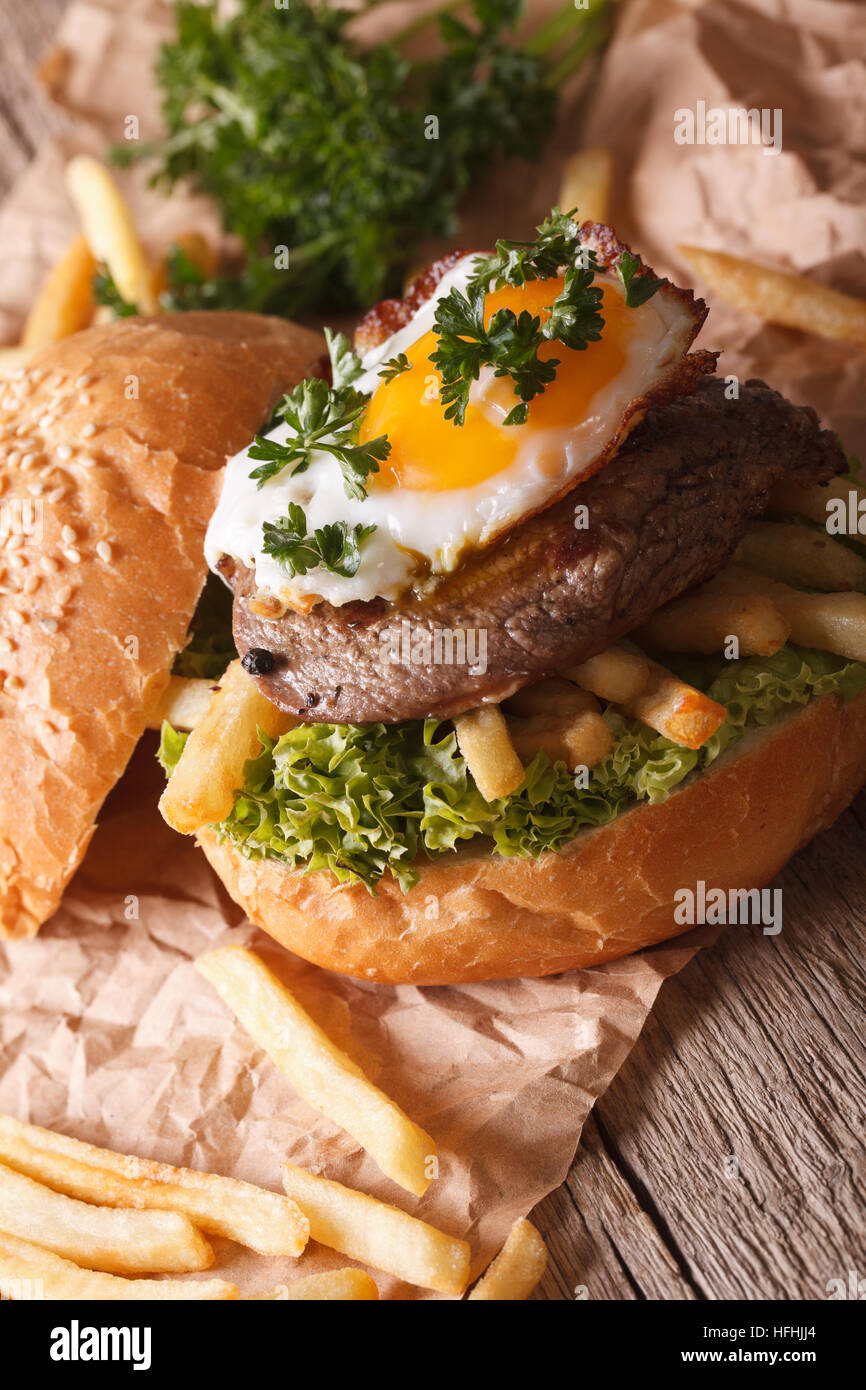 Homemade sandwich with beefsteak, fried egg and French fries close-up. vertical Stock Photo