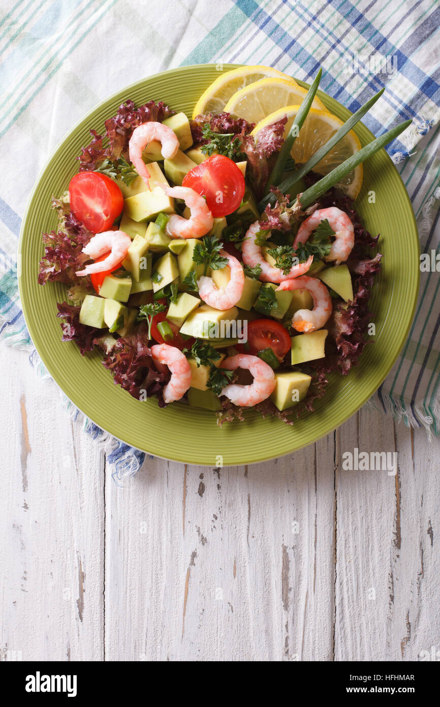 Tasty salad with avocado, shrimp and vegetables on a plate. vertical top view Stock Photo