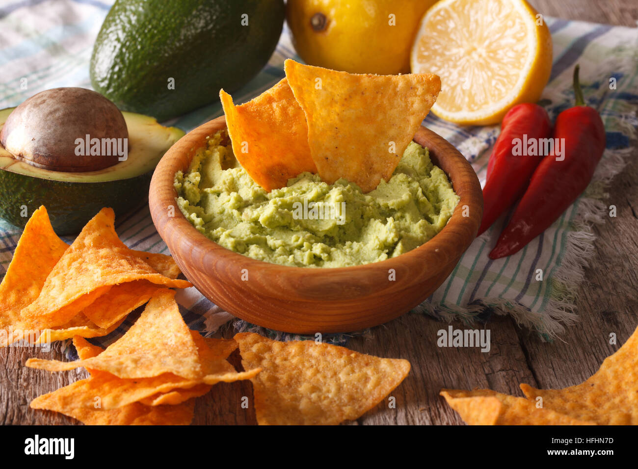 Corn nachos and guacamole sauce and ingredients closeup on the table. Horizontal, rustic Stock