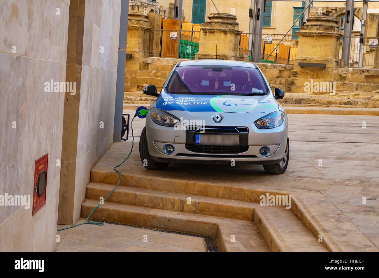 Renault Fluence Z.E. charging behind the new energy efficient parliament building of Malta in Valetta. This model is an electric version. Stock Photo