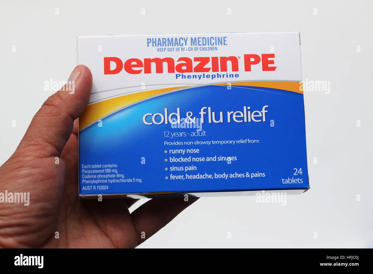 Hand holding a box of Demazin Cold and Flu Relief Tablet isolated against white background Stock Photo