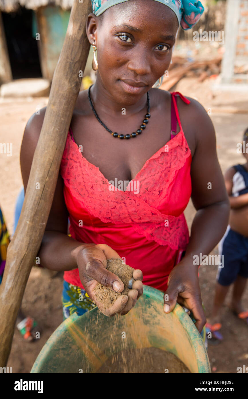 Kiniero, Guinea, 30th April 2015:  Wassaba Condé pounding rock in a mortar with her friend to extract gold. She sometimes extracts up to 8 grams per day or per week. Stock Photo