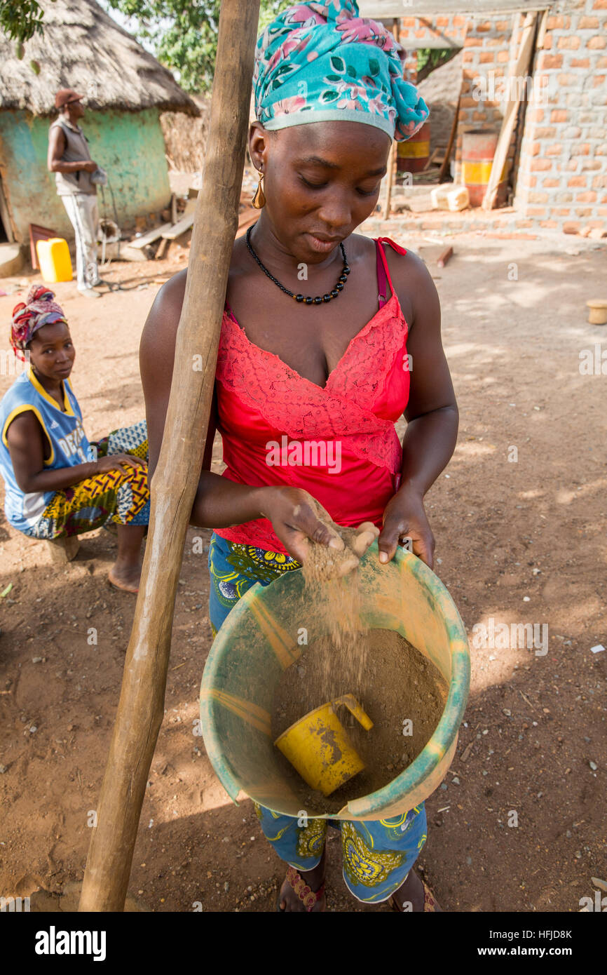 Kiniero, Guinea, 30th April 2015:  Wassaba Condé pounding rock in a mortar with her friend to extract gold. She sometimes extracts up to 8 grams per day or per week. Stock Photo
