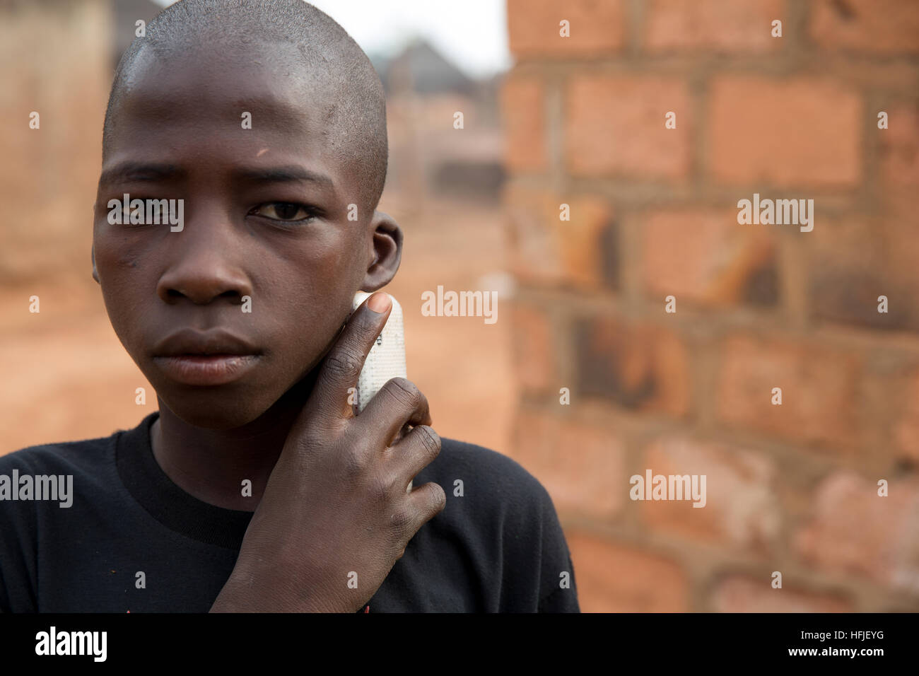 Koumban village, Guinea, 2nd May 2015; This area is above the proposed level of the Fomi dam and will be taking in displaced people. A young boy with his mobile phone. Stock Photo