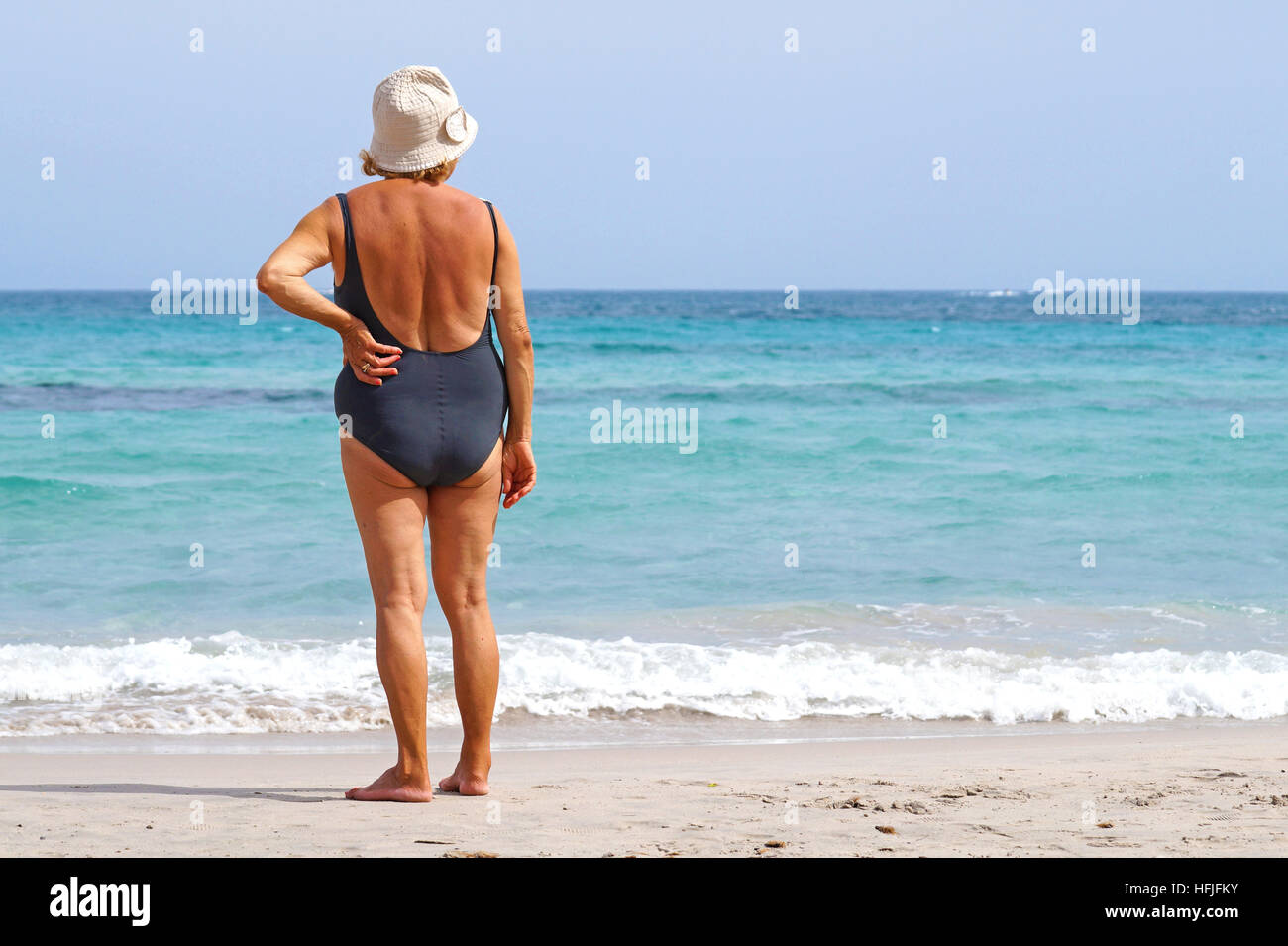 Senior woman looking the sea at beach . Rear view . Stock Photo