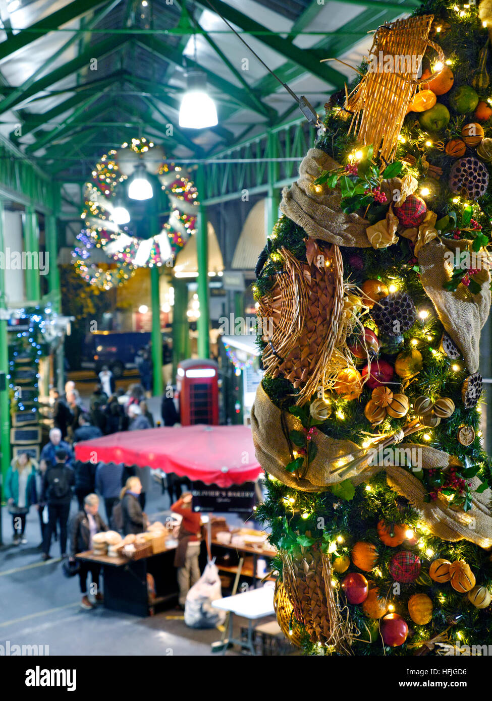BOROUGH MARKET CHRISTMAS Elevated view of late night cheese market stalls and tasting samples, with produce themed Christmas wreath hanging in foreground Borough Market Southwark London SE1 Stock Photo